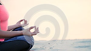 Healthy, young beautiful woman meditating, practicing yoga on the beach, by the sea, at sunrise, Relaxes muscles, mind