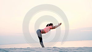 Healthy, young beautiful woman meditating, practicing yoga among the sand, on the beach, by the sea, river, at dawn, at