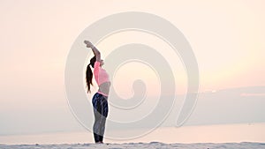 Healthy, young beautiful woman meditating, practicing yoga on the sea beach, at sunrise, Makes exercises for balance and