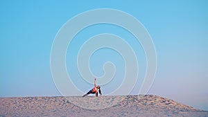 Healthy, young beautiful woman meditating, stretching, practicing yoga on the sea beach, at sunrise, Makes exercises for