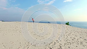 Healthy, young beautiful woman in sunglasses meditating, stretching, practicing yoga on the sea beach, at sunrise, Makes