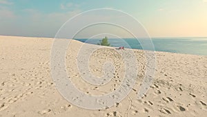 Healthy, young beautiful woman in sunglasses meditating, stretching, practicing yoga on the sea beach, at sunrise, Makes