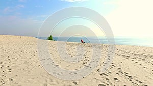 Healthy, young beautiful woman in sunglasses meditating, stretching, practicing yoga on the sea beach, at sunrise, Makes