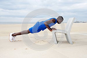 Healthy young man doing push ups on beach at the beach