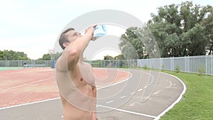 Healthy Young Man Drinking Water from the bottle outdoors.