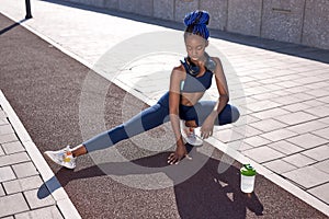 Healthy young pretty african american woman stretching her leg during exercise before work out