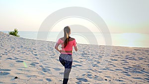 Healthy, young sports beautiful woman runs along the sand, on the beach, in summer, towards the sun, at the sunrise.