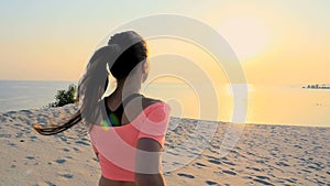 Healthy, young sports beautiful woman runs along the sand, on the beach, in summer, towards the sun, at the sunrise.