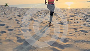 Healthy, young sports beautiful woman runs along the sand, on the beach, in summer, towards the sun, at the sunrise