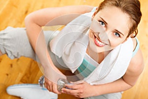 Healthy young sportswoman drinking water at gym