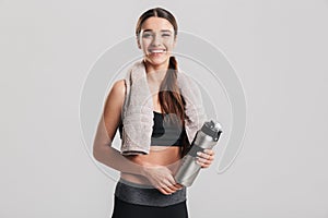 Healthy young sportswoman wearing tracksuit with towel looking o