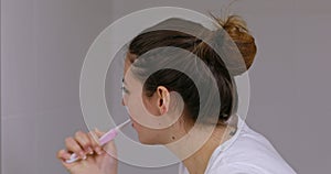 Healthy young woman brushing teeth in bathroom.