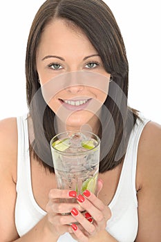 Healthy Young Woman Holding a Glass of Still Water with Ice and Lime