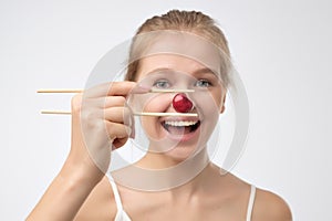 Healthy young woman holding one red cherry with sticks