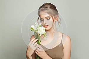 Healthy young woman holding white flowers on white background