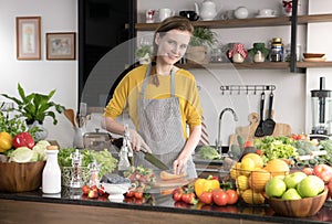 Healthy young woman in a kitchen preparing fruits and vegetables for healthy meal and salad