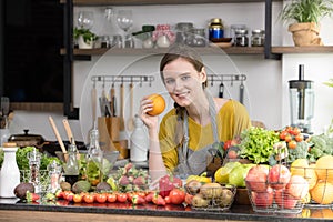 Healthy young woman in a kitchen preparing fruits and vegetables for healthy meal and salad