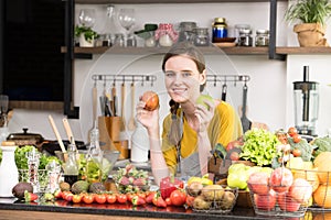 Healthy young woman in a kitchen preparing fruits and vegetables for healthy meal and salad