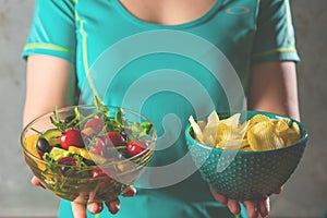 Healthy young woman looking at healthy and unhealthy food, trying to make the right choice