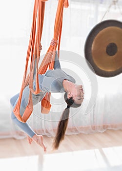 Healthy young women doing antigravity backward bending position in fly yoga hammock