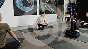 Healthy young women waiting for a yoga class to start in light loft studio sitting on black mats