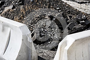 A heap of asphalt, stones and a barrier are at road building