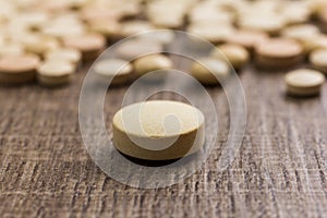 Heap of assorted beige capsules on wooden table.