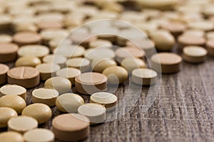 Heap of assorted beige capsules on wooden table.