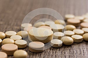 Heap of assorted beige capsules on wooden table.