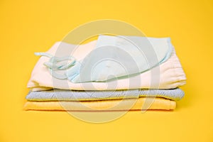 Heap of baby clothes on vibrant yellow background.