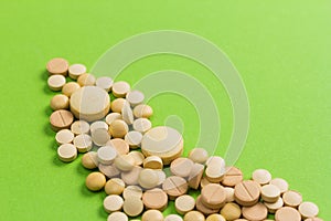 Heap of beige capsules on green table.