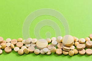Heap of beige capsules on green table.