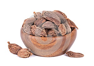 Heap of black cardamom pods in wooden bowl, isolated on white background. Black cardamon seeds. Clipping path.