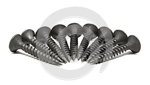 Heap of black steel screws arranged in a radial pattern