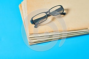 Heap of blank magazines, newspapers or some documents and modern glasses on blue desk