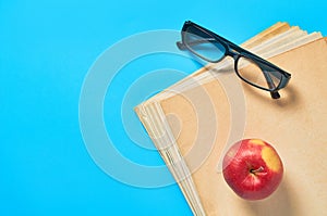 Heap of blank magazines, newspapers or some documents and modern glasses, red apple on blue desk