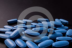 Heap of blue pills on a black background photo