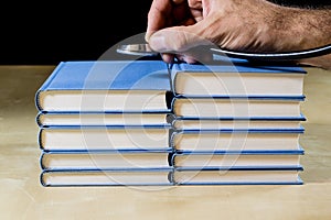 Heap of books reading on a wooden table. Beside lies and stethoscope. Black background.