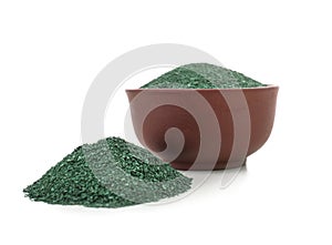 Heap and bowl of spirulina algae powder on white