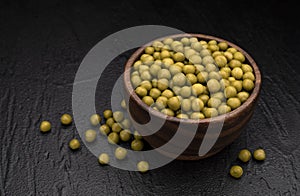 Heap of canned green peas on black background