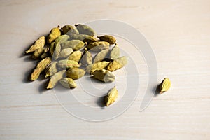 A heap of cardamom isolated on a wooden background. Its scientific name is Elettaria cardamomum photo