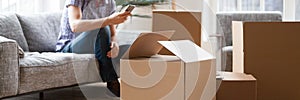 Heap cardboard boxes on foreground man with phone on background