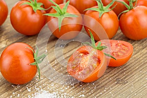 Heap of cherry tomatoes with one cut in half and pinch of salt