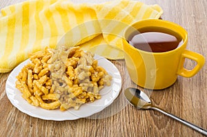 Heap of chuck-chuck with sesame, cup of tea, teaspoon