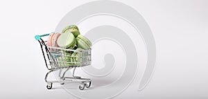 heap of color macaroons in a toy shopping cart on white background. banner format