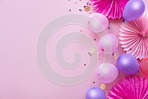 Heap of colorful balloons, confetti and paper flowers on pink table top view. Birthday party background. Festive greeting card.