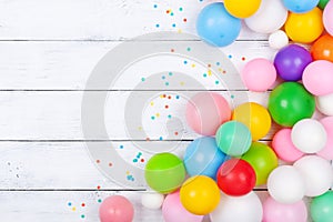 Heap of colorful balloons and confetti on white table top view. Festive or party background. Flat lay. Birthday greeting card