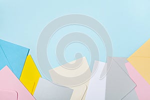 Heap of colorful envelopes on blue working desk top view. Mockup for business mail, blogging and office correspondence. Flat lay.