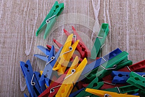 a heap of colorful plastic clothespins are lying on a wooden table