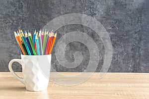 Heap of colorfull pencils on a wooden desk and gray background